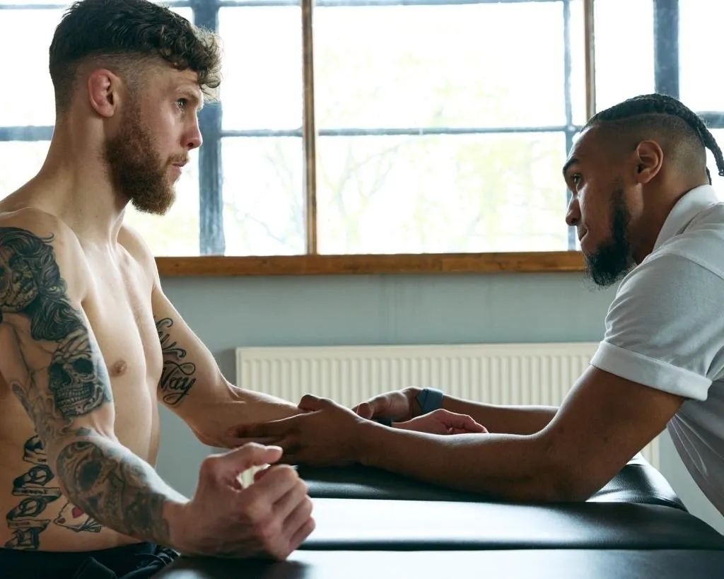 Physiotherapist assessing a fighter's wrist during a consultation